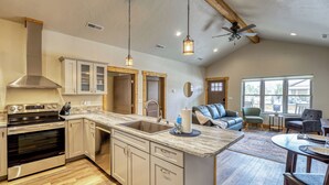 A spacious kitchen with a large island, built-in oven, and a ceiling fan.