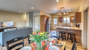 A modern kitchen with wooden cabinets, a central island, and a dining area with a table set for two.