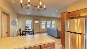A kitchen with a stainless steel refrigerator, wooden cabinets, a granite countertop, and a chandelier.