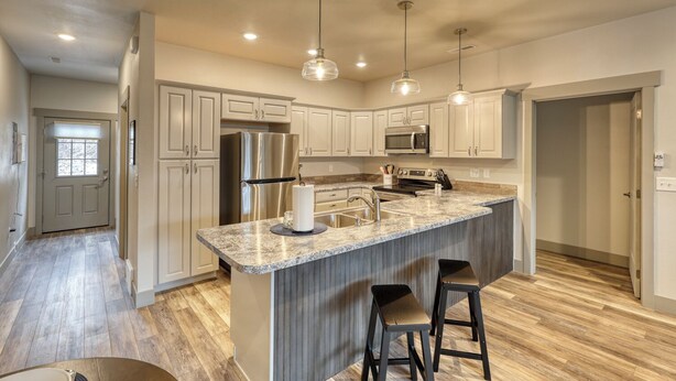 A modern kitchen with a large island, stainless steel appliances, and pendant lighting.