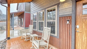 A covered porch with two rocking chairs and a wooden door with a keypad lock.
