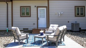 Un patio exterior con dos sillas color beige, una mesita y un tapete decorativo.