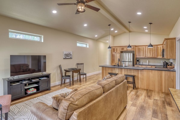 A spacious living room with a large TV, a sofa, and a dining area with chairs.