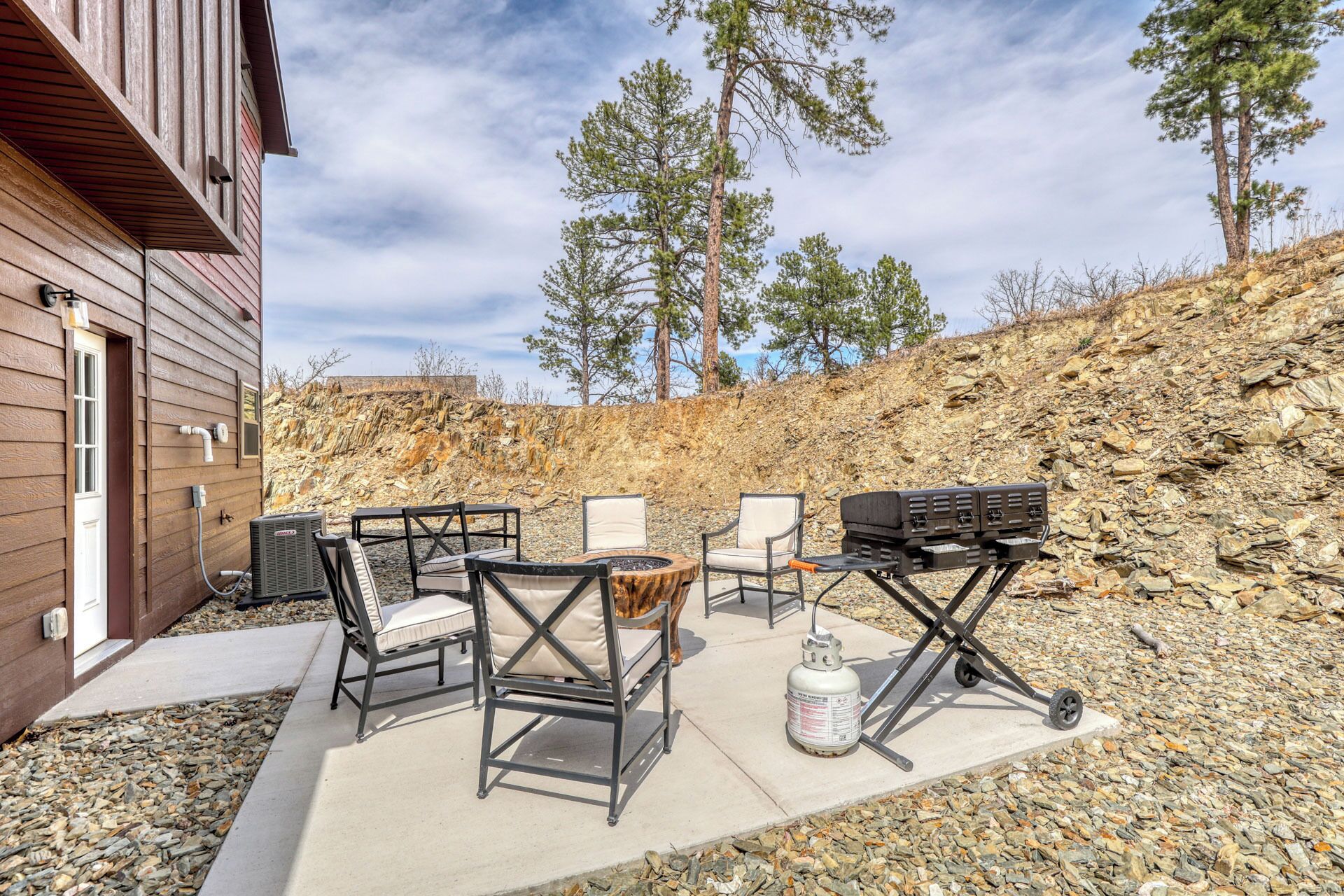 Une terrasse extérieure avec un barbecue, des chaises et un sol en béton.