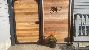 A wooden door with an octopus design, a potted plant with red and yellow flowers, and a stone-tiled entrance. - Similk Beach View Studio for two! 
Central HUB to San Juans and Skagit Valley! (Anacortes)