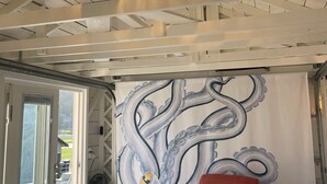 A room with a ceiling fan, a red armchair, a large octopus mural, and a view through a glass door. - Similk Beach View Studio for two! 
Central HUB to San Juans and Skagit Valley! (Anacortes)