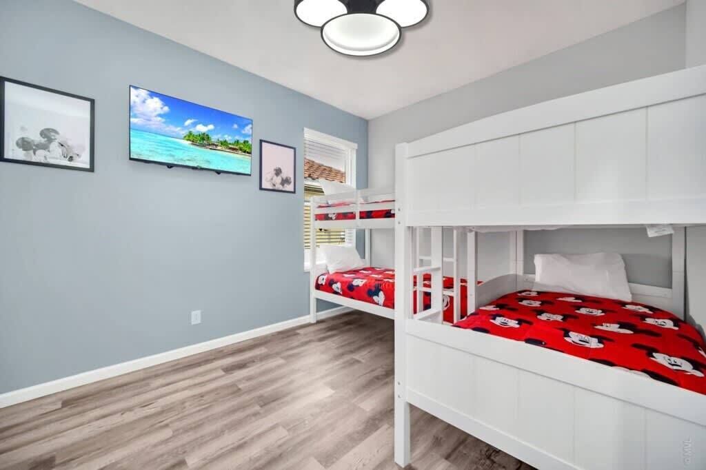 A room with a bunk bed, a flat-screen TV, and framed pictures on the wall.