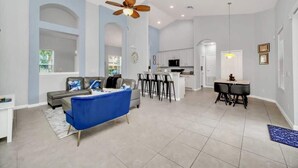 A spacious living area with a sofa, a dining table, and a kitchen in the background. - Newly Remodeled Disney Vacation Home (Davenport)