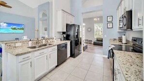 A modern kitchen with white cabinets, granite countertops, and stainless steel appliances. - Newly Remodeled Disney Vacation Home (Davenport)