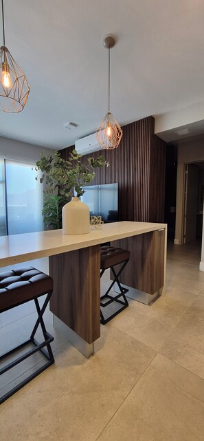 Una cocina moderna con una isla central, luces colgantes y una planta en maceta.