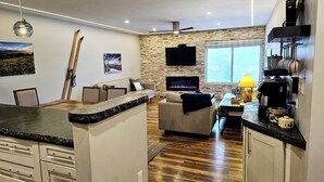 A modern kitchen with a stone backsplash, wooden flooring, and a built-in TV. - Center of Downtown Breck, walk to slopes and Main Street! Steps to Riverwalk. (Breckenridge)