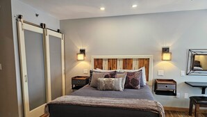 A bedroom with a bed, bedside tables, a bench, a wardrobe, and a mirror. - Center of Downtown Breck, walk to slopes and Main Street! Steps to Riverwalk. (Breckenridge)