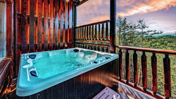 Un bain à remous sur une terrasse en bois, avec vue sur un paysage boisé.