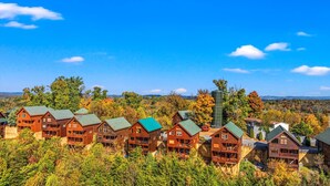 Un ensemble de chalets en bois, dotés de plusieurs étages et de balcons, entourés d’une forêt dense et d’un feuillage automnal.