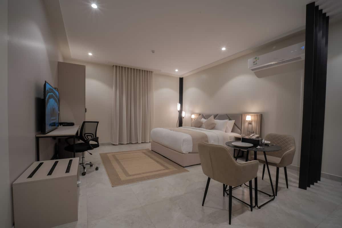 Une chambre d’hôtel moderne équipée d’un lit, d’un bureau, d’une chaise et d’un petit coin repas.