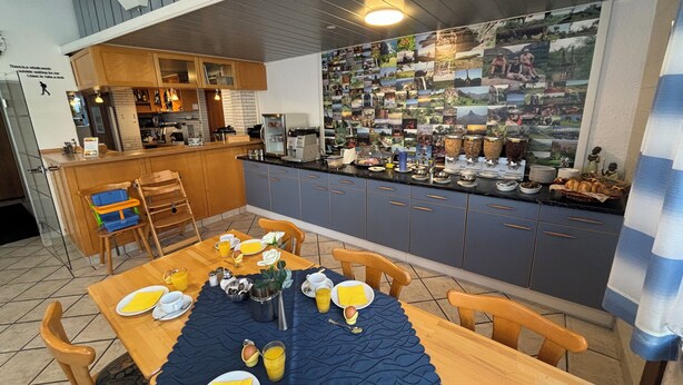 Una cocina moderna con comedor, armarios de madera y una pared de fotografías.
