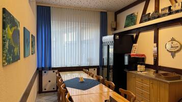 Ein Essbereich mit einem langen Holztisch, Stühlen, einem Kühlschrank, einer Zapfsäule für Bier und Kunstwerken an den Wänden.
