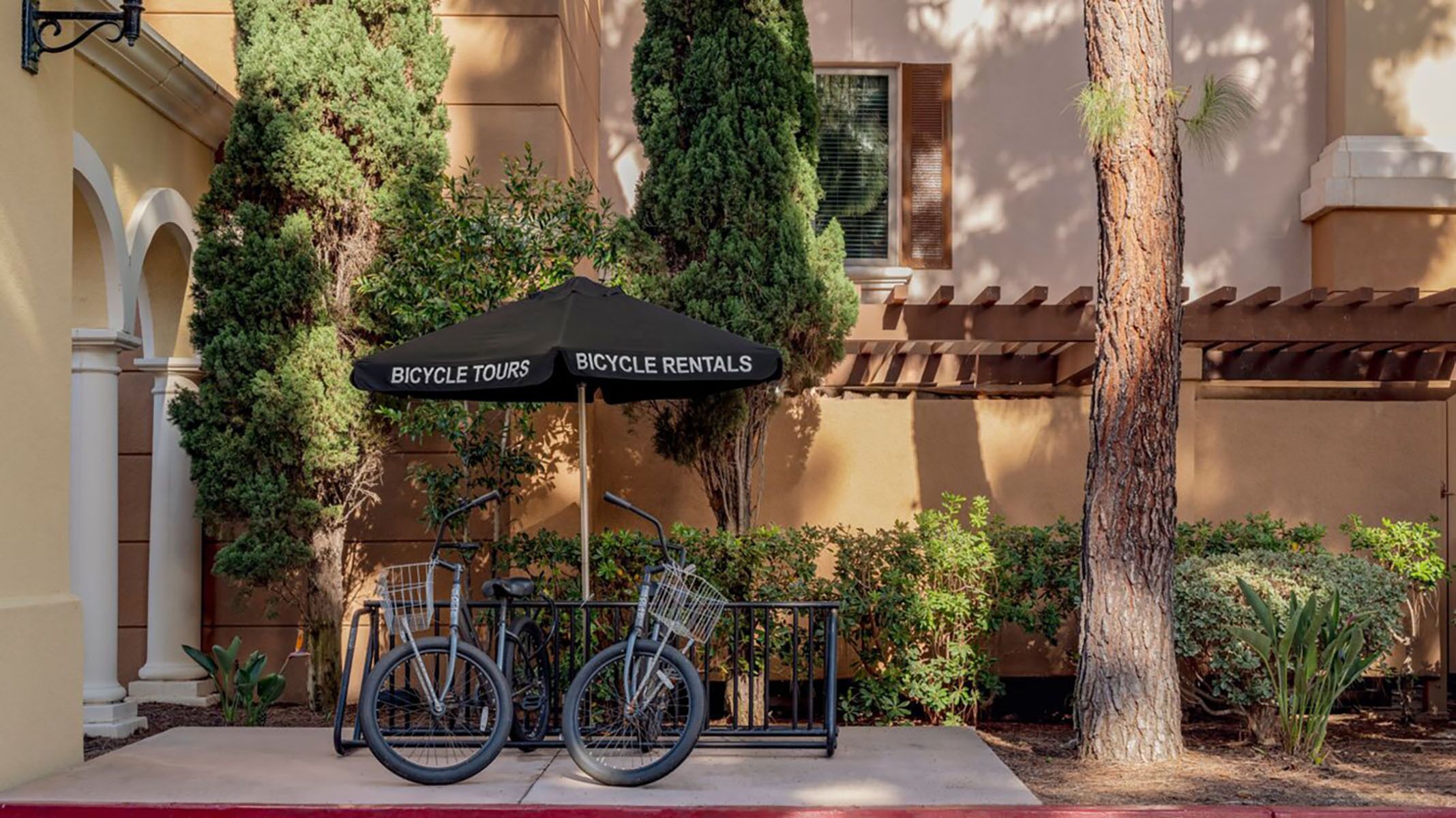 Una estación de alquiler de bicicletas con dos bicicletas y un toldo que dice 'BICYCLE TOURS' y 'BICYCLE RENTALS'.