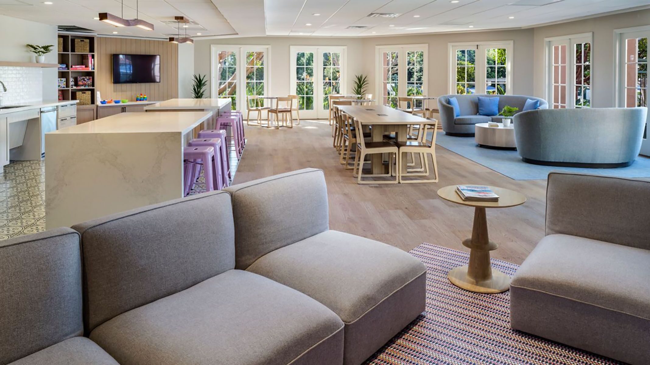 Una sala de estar moderna con un sofá grande, una mesa de centro y un comedor con sillas y una mesa.