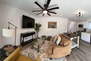 A modern living room with a ceiling fan, a flat-screen TV, a sofa, and a coffee table.