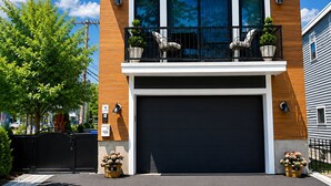 Une maison moderne à deux étages, dotée d’un grand garage, d’un balcon avec mobilier d’extérieur et d’une cour avant bien entretenue.