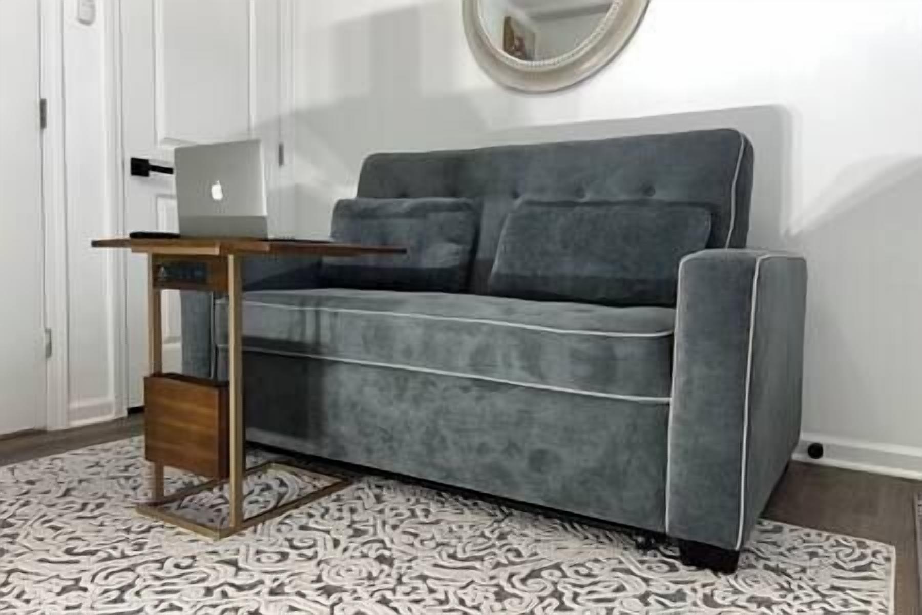 Ein graues Sofa mit einem Holztischchen und einer kleinen Holzleiter.