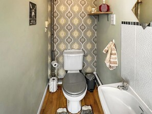 Une salle de bain comprenant des toilettes, une baignoire, un rideau de douche, un porte-serviettes et une poubelle.