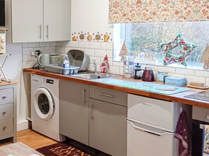 A kitchen with a washing machine, a sink, and a window with a view of trees. - 1 bedroom accommodation in Woodbury Salterton, near Exmouth (Woodbury Salterton, near Exmouth)