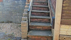A set of outdoor stone steps leading down to a gravel area, surrounded by wooden walls and a metal gate. - 1 bedroom accommodation in Woodbury Salterton, near Exmouth (Woodbury Salterton, near Exmouth)