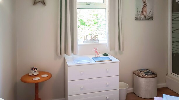 A bedroom with a window, a dresser, a small table, and a picture on the wall. - 1 bedroom accommodation in Woodbury Salterton, near Exmouth (Woodbury Salterton, near Exmouth)