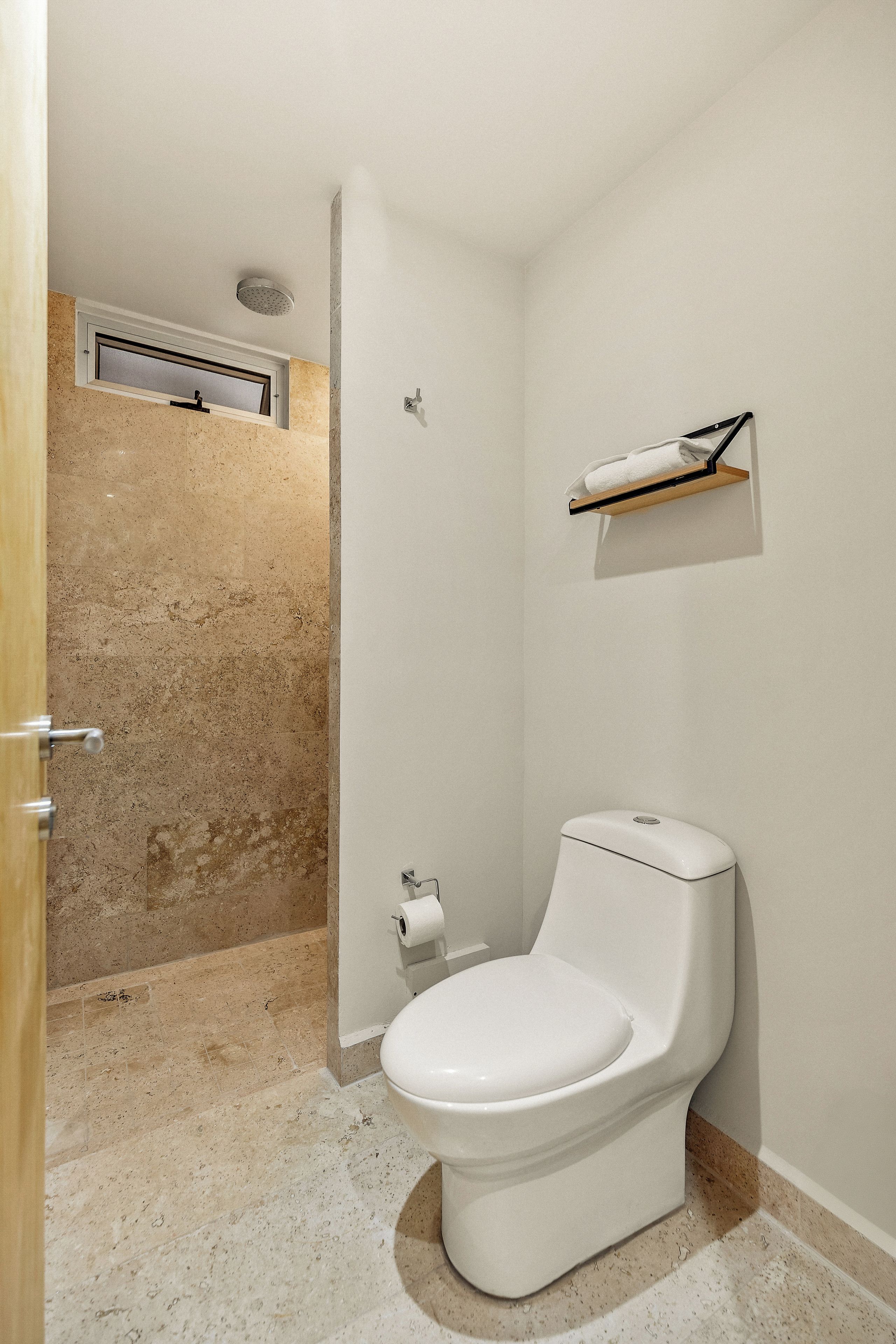 A bathroom with a toilet, a shower area, and a towel rack.
