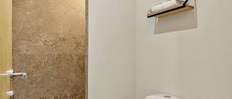 A bathroom with a toilet, a shower area, and a towel rack.