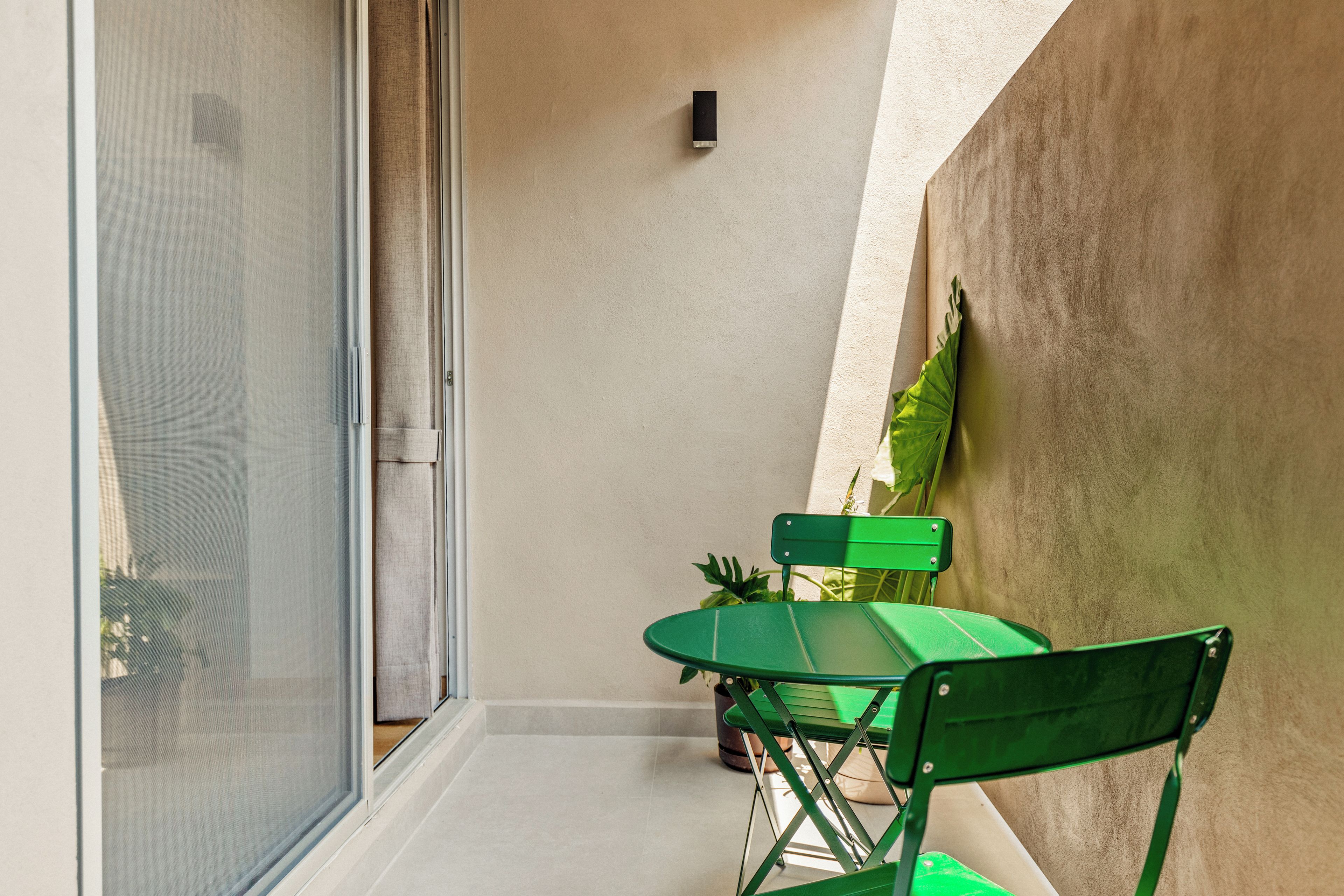 A small outdoor seating area with a table and two chairs, a potted plant, and a sliding glass door.