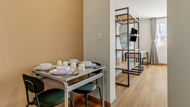 A dining area with a table set for four, chairs, and a bookshelf in the background. - Musgo by Homirent (Querétaro)