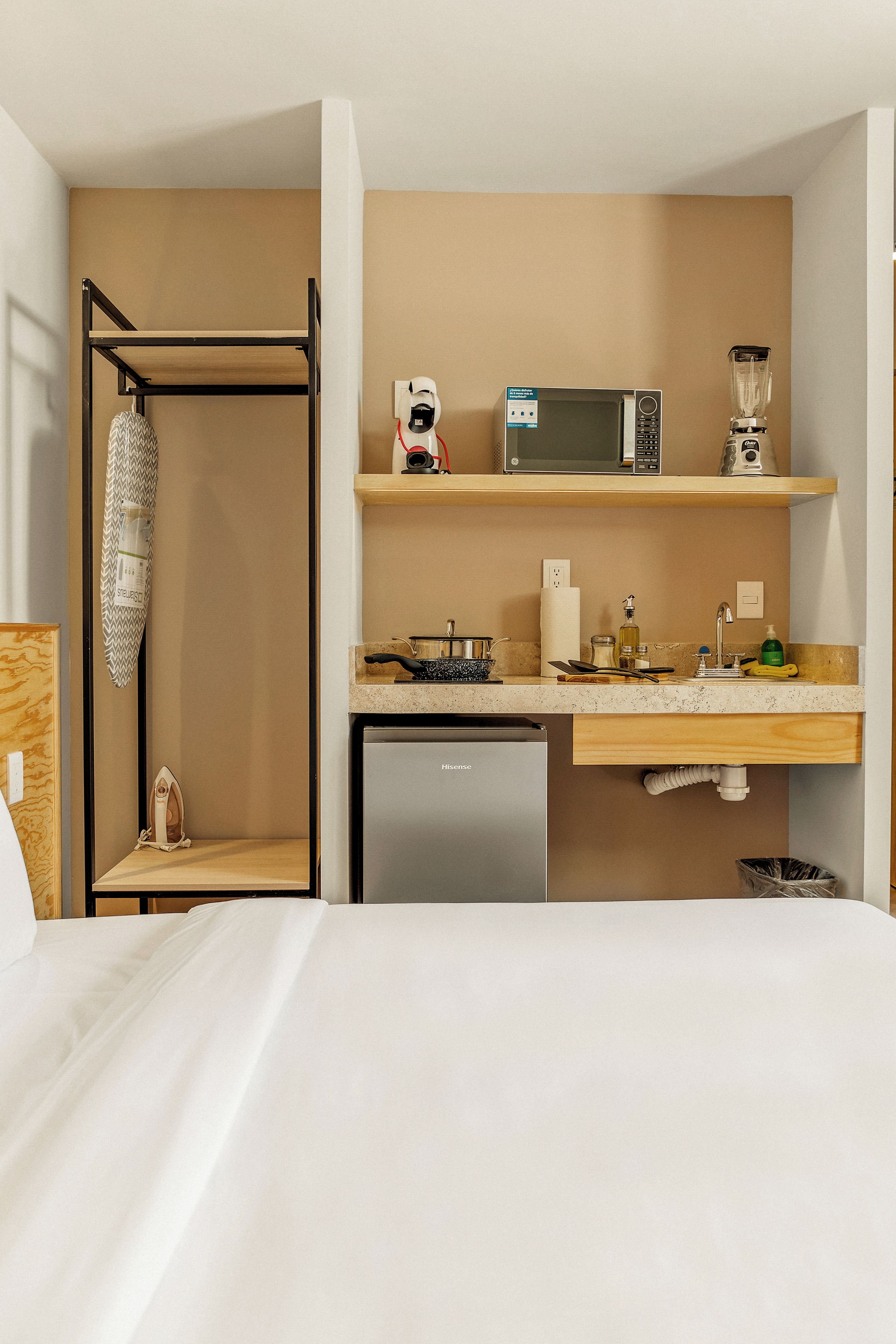 Quarto de hotel compacto com cozinha americana, incluindo micro-ondas, liquidificador e minibar.