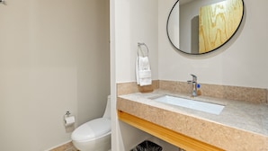 Een badkamer met een wit toilet, een wastafel met spiegel, en een handdoek aan een metalen ring.