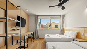 A hotel room with two beds, a desk, a TV, and a window with a city view. - Musgo by Homirent (Querétaro)