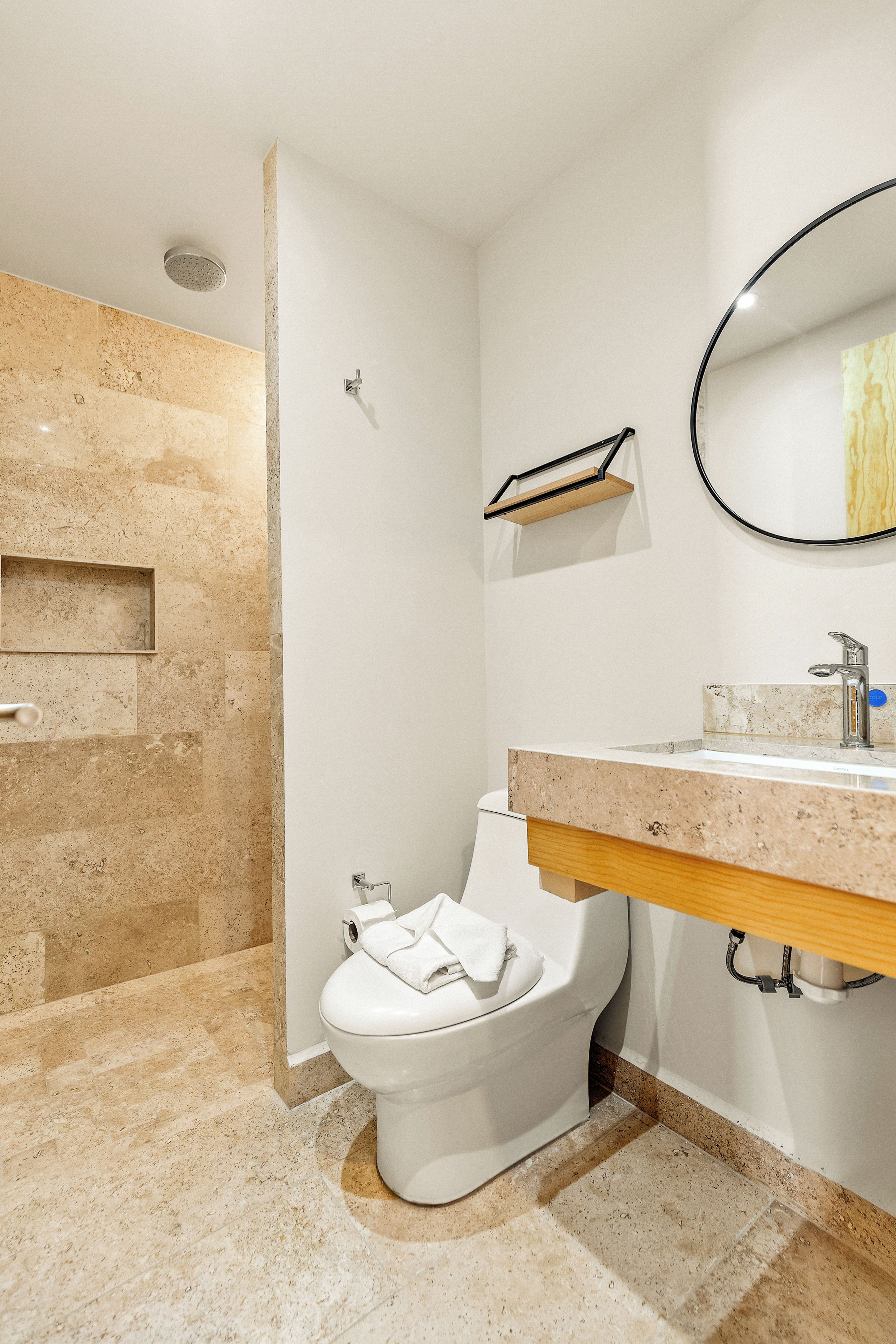 Un baño con inodoro, lavabo, espejo y ducha.