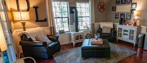 Una sala de estar acogedora con chimenea, un sofá de cuero negro, una mesa de comedor y un ventilador de techo.