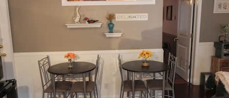A dining area with two round tables, chairs, a decorative vase, and a sign on the wall.