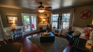 A living room with a fireplace, a ceiling fan, a dining table, and a cozy seating area. - Drakeslanding Inn (Shaver Lake)
