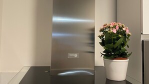 A stainless steel range hood with a 'turboair' label, a potted plant with pink flowers, and a modern kitchen backsplash. - Casa Valentina 2 (Perugia)