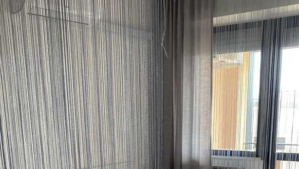 A hotel room with a bed, a bedside table, and a curtain divider. - Casa Valentina 2 (Perugia)