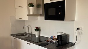 A modern kitchen with white cabinets, a stainless steel sink, a microwave, and a coffee maker on the countertop. - Casa Valentina 2 (Perugia)