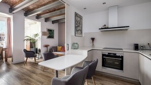 A modern kitchen with a built-in oven, white cabinetry, and a dining area with grey chairs. - Bright and Quiet Duplex Apartment (Barcelona)