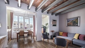 A modern living room with a dining area, wooden flooring, and exposed beams. - Bright and Quiet Duplex Apartment (Barcelona)