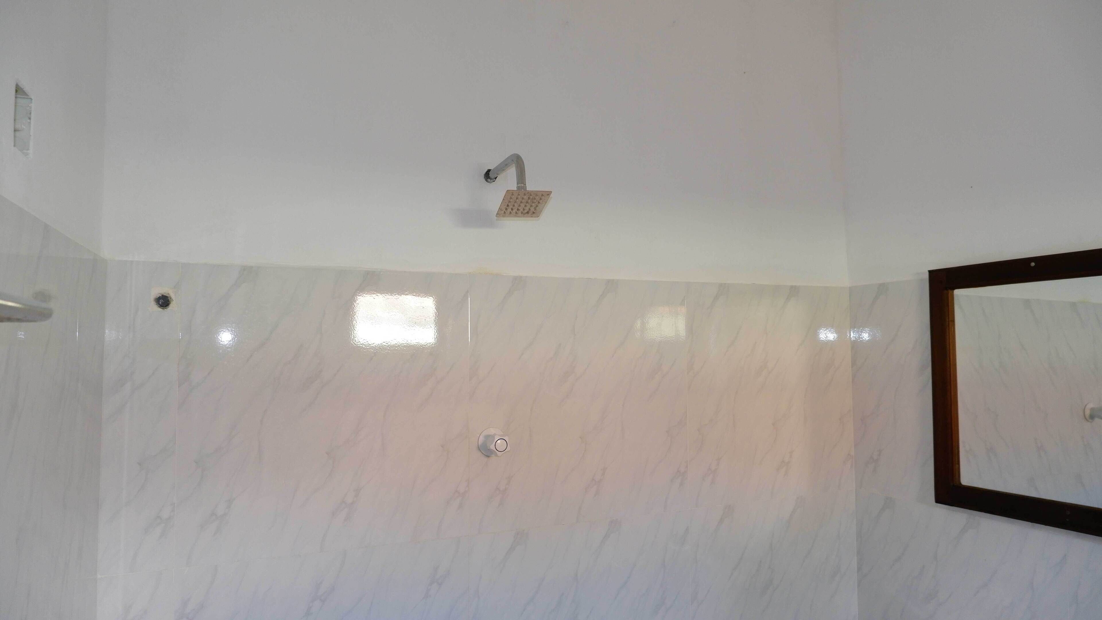 A bathroom with a shower, a mirror, and a tiled wall.