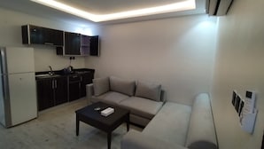 A compact living space with a kitchenette, a sofa, a coffee table, and a refrigerator. - Jeddah Grand Beach (Jeddah)