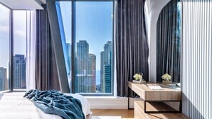 Ein modernes Schlafzimmer mit großem Fenster, einem Bett, einem Nachttisch und Blick auf Stadtgebäude.