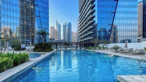 Ein Pool mit Blick auf die Stadt, umgeben von Liegestühlen und Grünpflanzen.